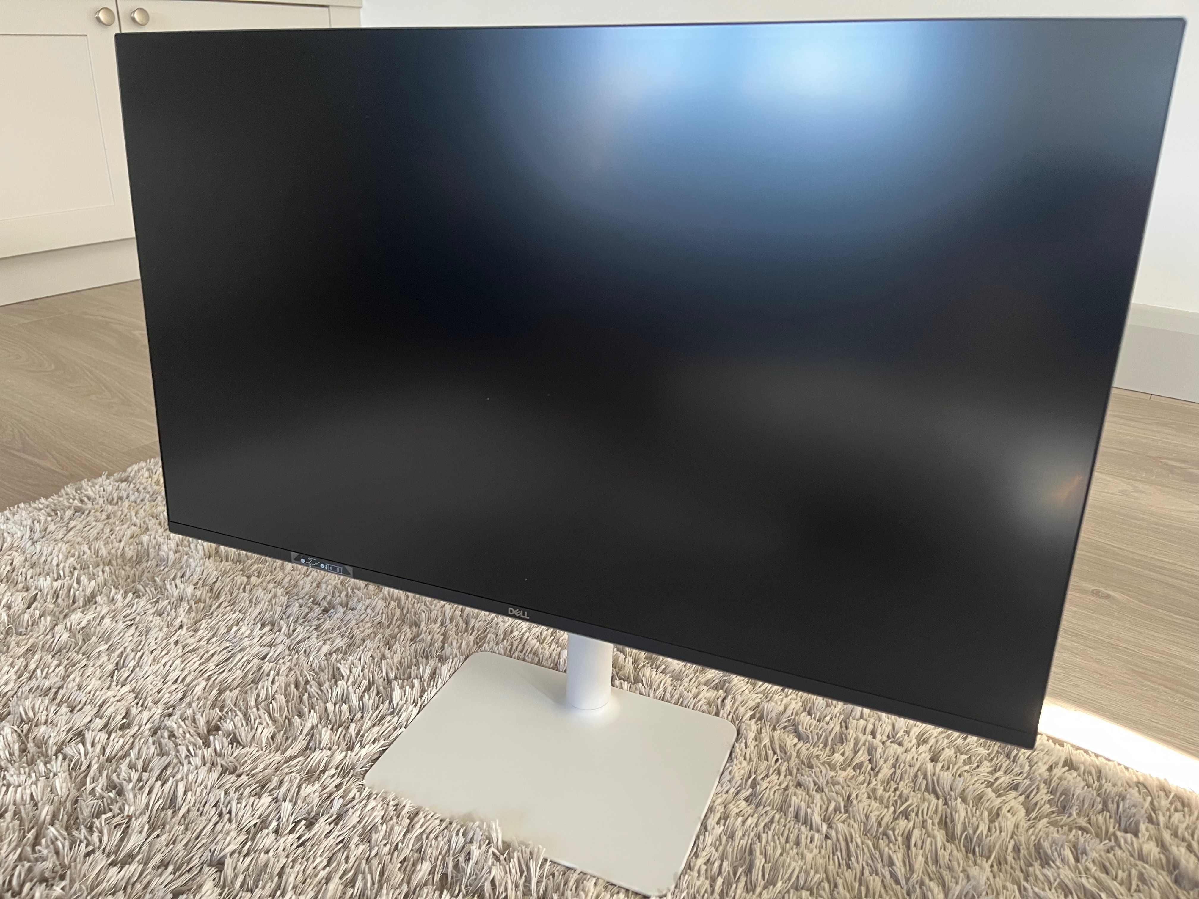 The monitor sits upright. The display and the bezel are black. It has tape over the easy access ports.