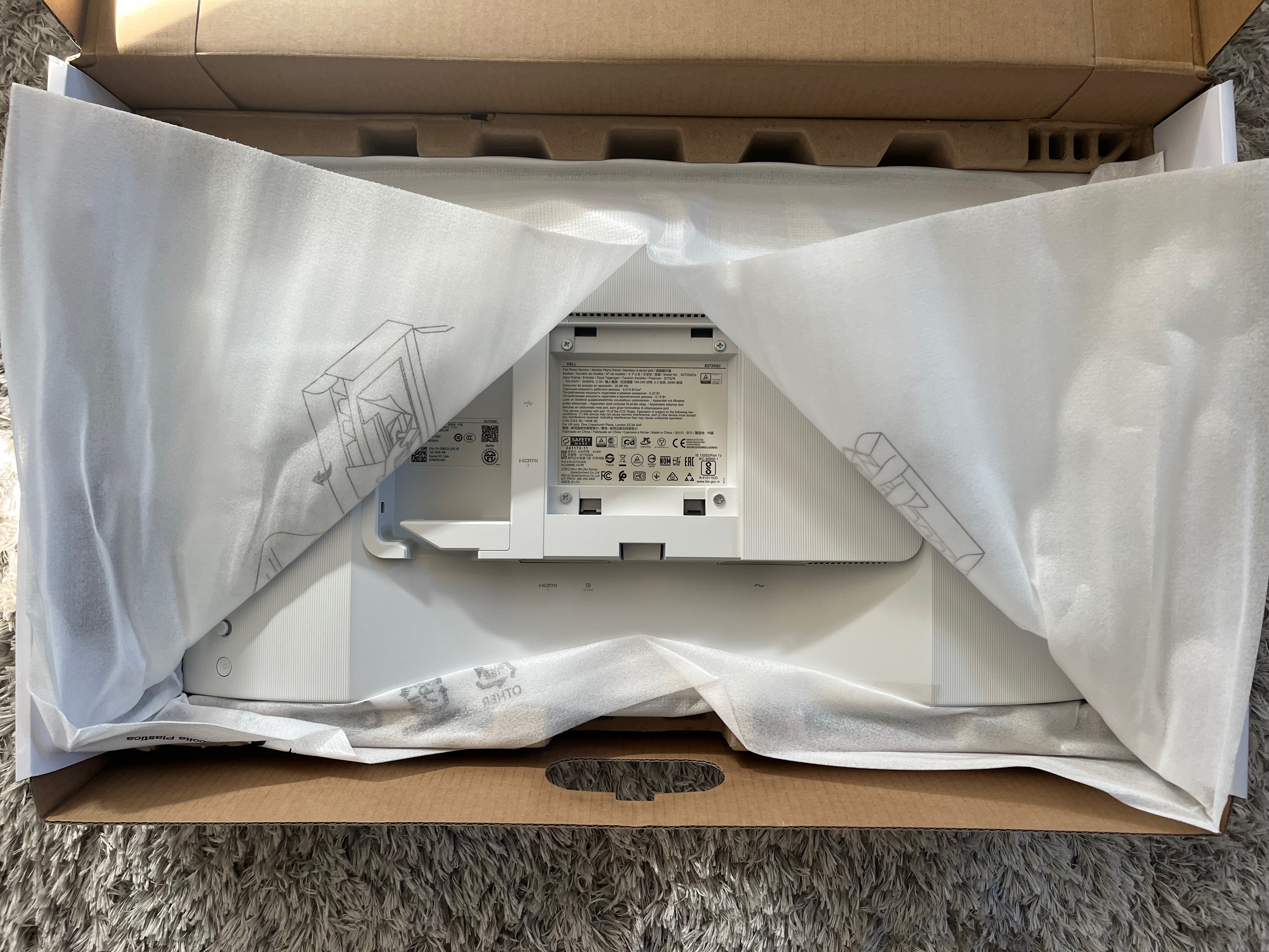 The monitor sits below the accessory tray. The foam has a slit down the middle to allow easy access to attatch the stand.